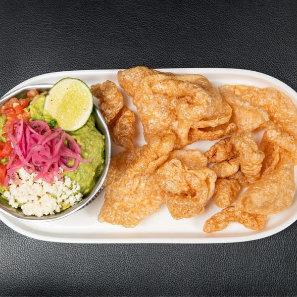 Guacamole with lime, pico de gallo, pickled onions, and cotija cheese, served with chicharrones.