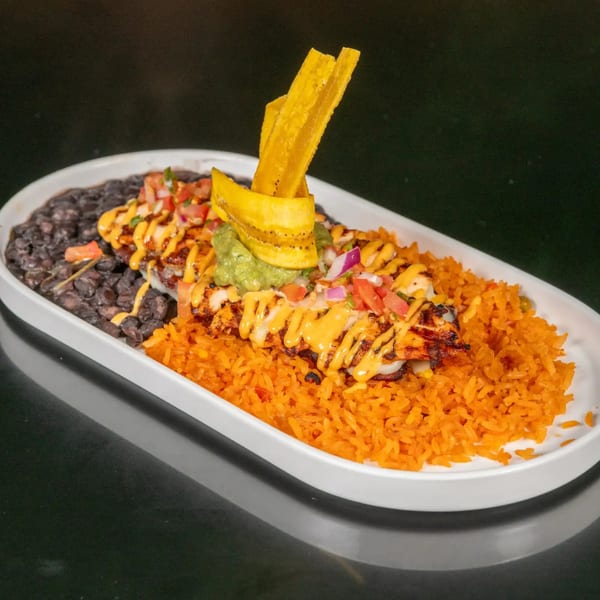 Grilled chicken with cheese sauce, pico de gallo, guacamole, plantain chips, black beans, and orange rice.