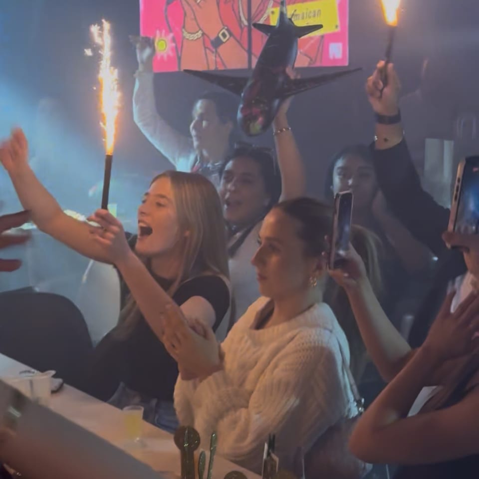 Excited patrons at La Buena Vida celebrating with sparklers and a decorative airplane.