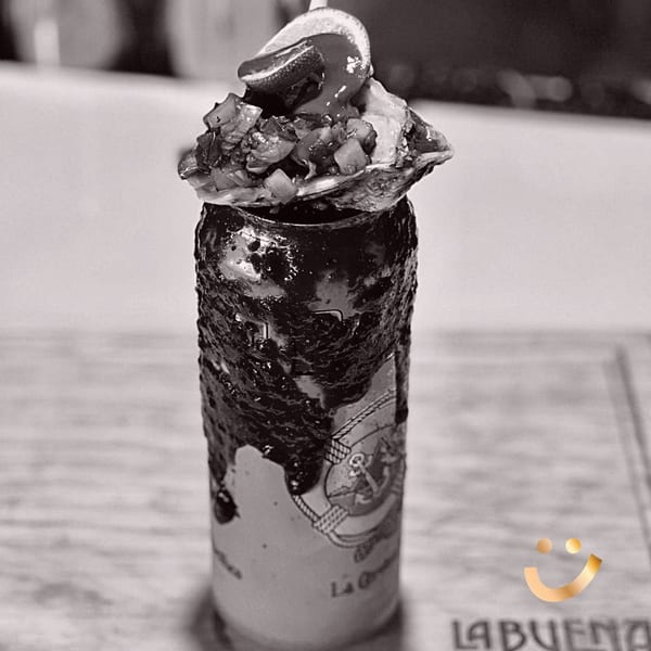 Black and white close-up of a La Buena Vida michelada topped with an oyster and lime.
