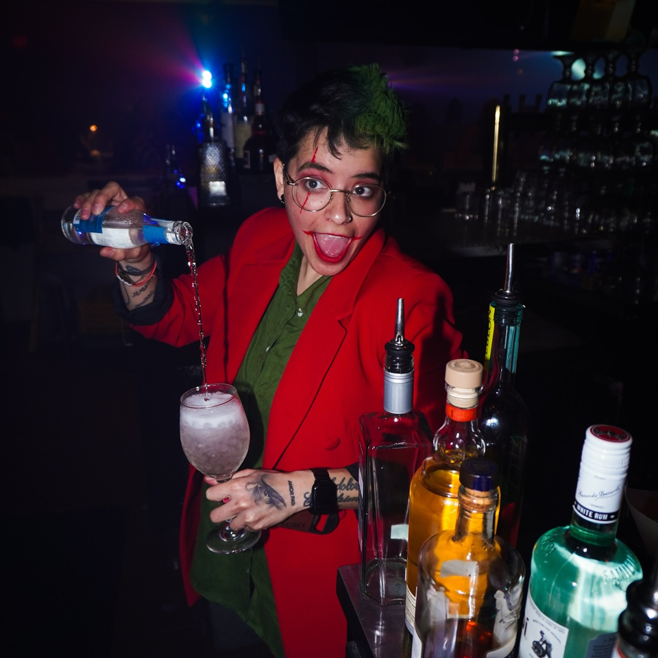 A bartender with Joker-inspired makeup pours a drink at La Buena Vida.