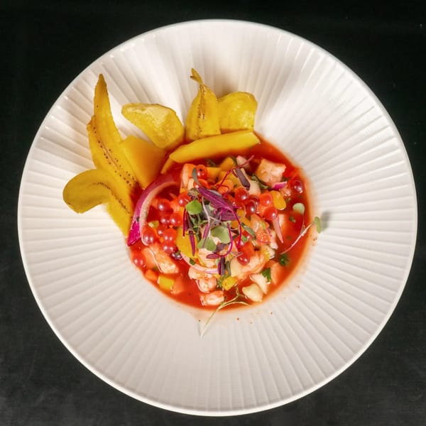 Vibrant ceviche with shrimp, mango, red onions, and microgreens, garnished with plantain chips.