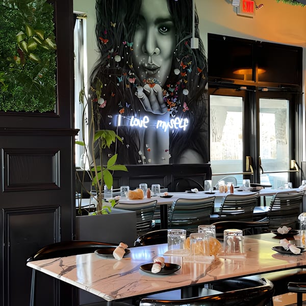 La Buena Vida dining room with a large mural of a woman blowing butterflies and a neon "I love myself" sign.